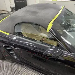 Czarny materiał na dach cabrio, zabezpieczony żółtą taśmą, gotowy do renowacji.