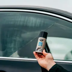 Dłoń trzyma puszkę preparatu K2 FOX ANTI-FOG, który zapobiega parowaniu szyb w samochodzie.