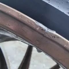 Pęknięta felga aluminiowa z widocznym uszkodzeniem i kroplami wody.