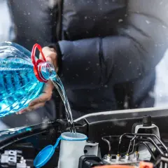 Zamarznięty płyn do spryskiwaczy? Wlej nowy, niebieski płyn z dużej butelki do zbiorniczka pod maską samochodu.