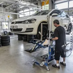 Mechanik sprawdza opony samochodu na podnośniku, przygotowując go do homologacji opon.