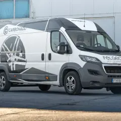 Biały van z grafiką felgi na boku. Idealny dobór felg do auta to klucz do stylu i bezpieczeństwa.