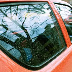 Widok na pomarańczowy samochód z widocznymi śladami żywicy na szybie. Zastanawiasz się, czym zmyć żywicę z szyby?