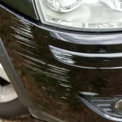 Głębokie rysy na czarnym zderzaku, widać ile lakieru na zderzak zostało uszkodzone.