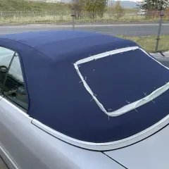 Granatowy dach cabrio w trakcie szycia, z widocznymi białymi nićmi mocującymi.