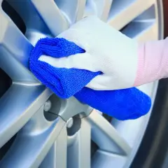 Ręka w białej rękawiczce czyści srebrną felgę niebieską ściereczką. Może to być część procesu czyszczenia felg WD40.