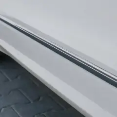 Usuwanie rys z chromu na listwie progowej białego samochodu.