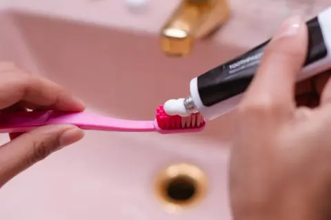 Usuwanie rys z plastiku pasta do zębów. Biała pasta nakładana na różową szczoteczkę.