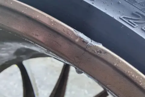 Pęknięta felga aluminiowa z widocznym uszkodzeniem i kroplami wody.
