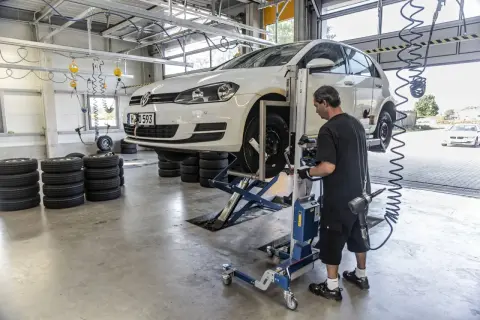 Mechanik sprawdza opony samochodu na podnośniku, przygotowując go do homologacji opon.