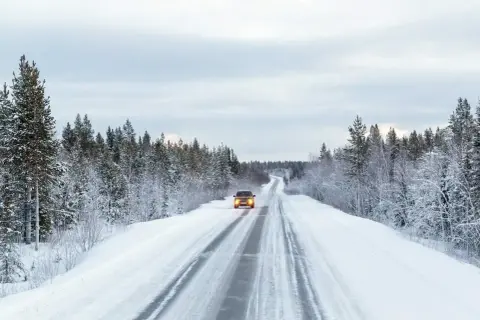 Samochód z oponami Nexen Winguard Sport 2 pokonuje ośnieżoną drogę przez zimowy las.