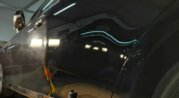 Widoczne są zarysowania i hologramy na czarnym lakierze, czekające na renowację lakieru samochodowego.