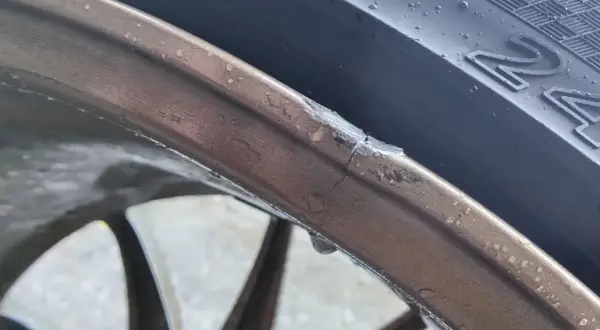 Pęknięta felga aluminiowa z widocznym uszkodzeniem i kroplami wody.