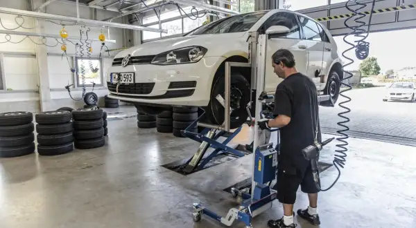 Mechanik sprawdza opony samochodu na podnośniku, przygotowując go do homologacji opon.
