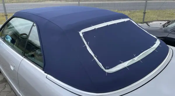 Granatowy dach cabrio w trakcie szycia, z widocznymi białymi nićmi mocującymi.
