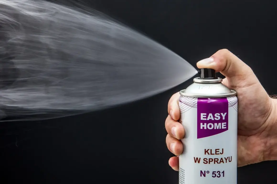 Dłoń trzyma puszkę z klejem w sprayu, który jest idealny, by przykleić podsufitkę w samochodzie.