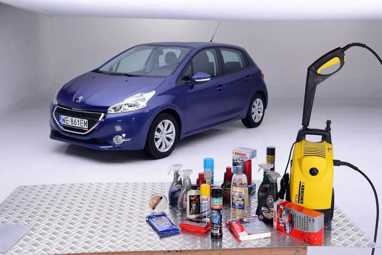 Niebieski Peugeot 208 obok myjki ciśnieniowej i zestawu kosmetyków samochodowych. Gdy nie ma szamponu, można użyć alternatywnych środków do umycia samochodu.
