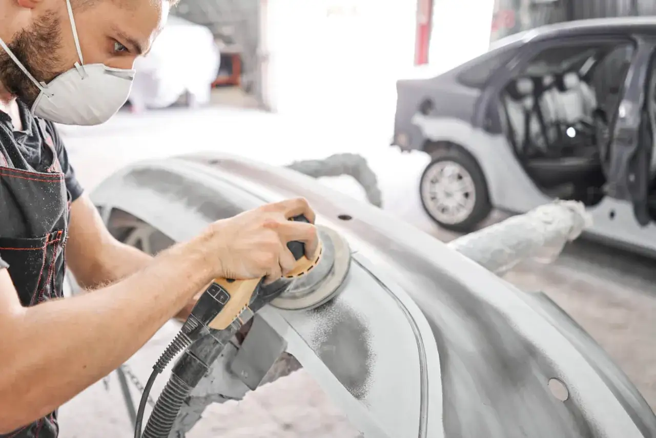 Mechanik w masce szlifuje podkład epoksydowy na zderzaku. Pytanie: jakim papierem szlifować podkład epoksydowy?