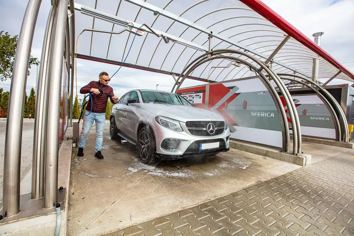 Mężczyzna myje srebrnego Mercedesa na myjni bezdotykowej. Poznaj myjnia bezdotykowa triki, by Tw&oacute;j samoch&oacute;d lśnił jak nowy!