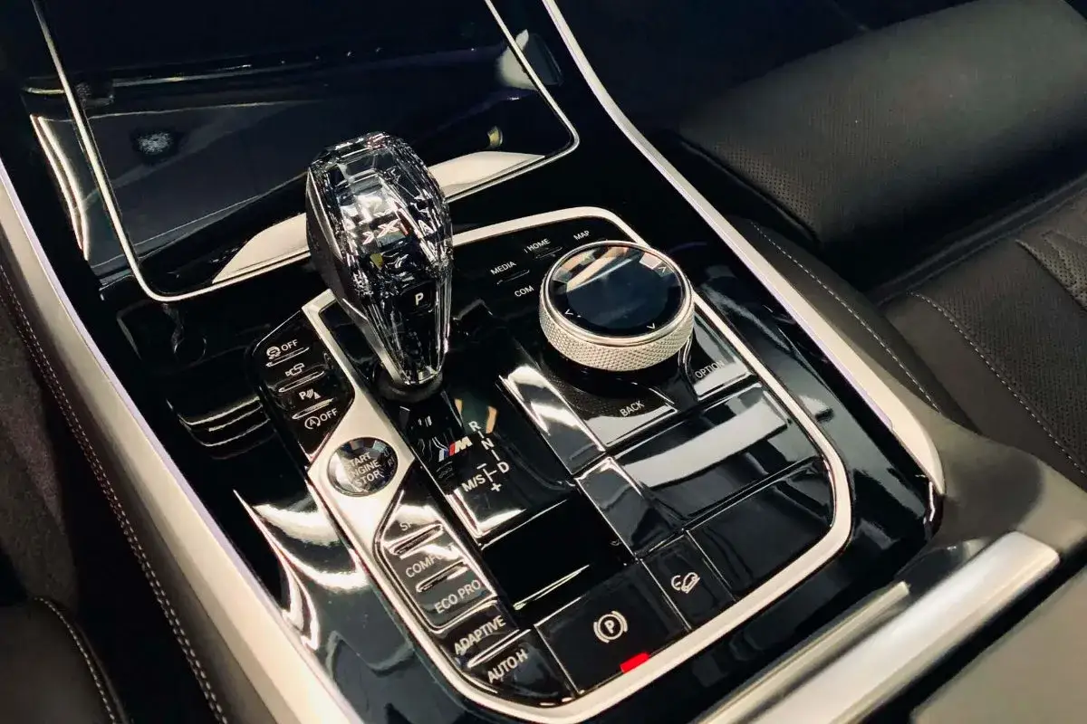 Błyszczący panel środkowy z kryształową dźwignią zmiany bieg&oacute;w i przyciskami, efekt profesjonalnego auto detailing.