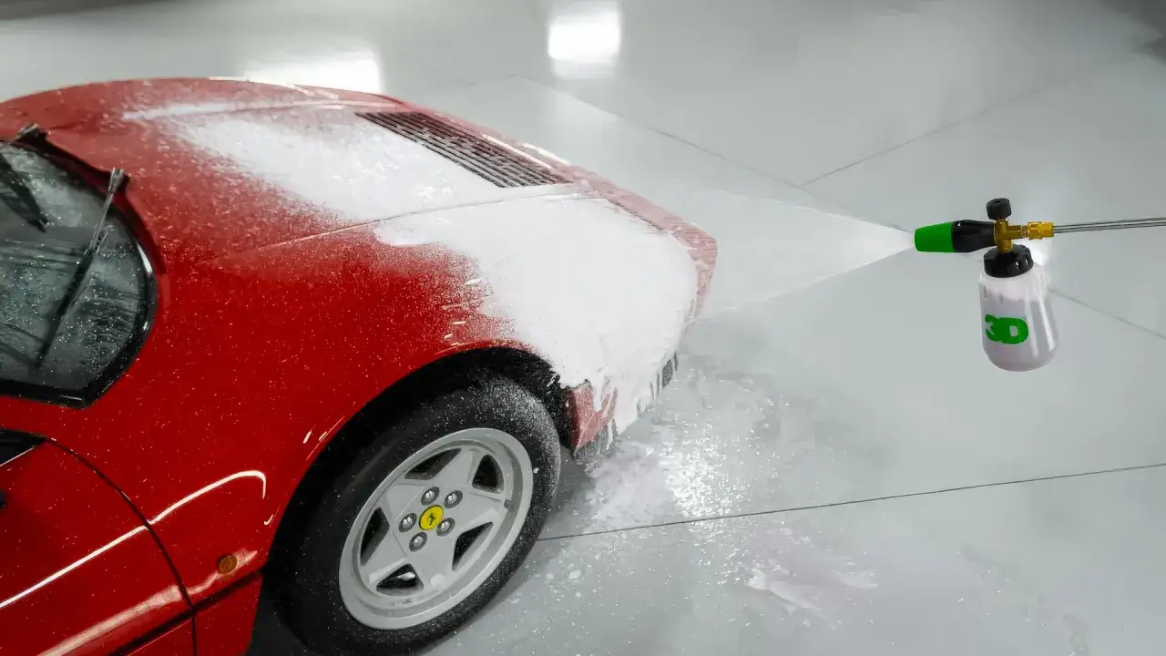 Czerwone Ferrari pokryte pianą z myjki ciśnieniowej. To pierwszy etap mycia, czyli prewash – co to znaczy? To wstępne spłukanie i nałożenie piany, by rozpuścić brud.