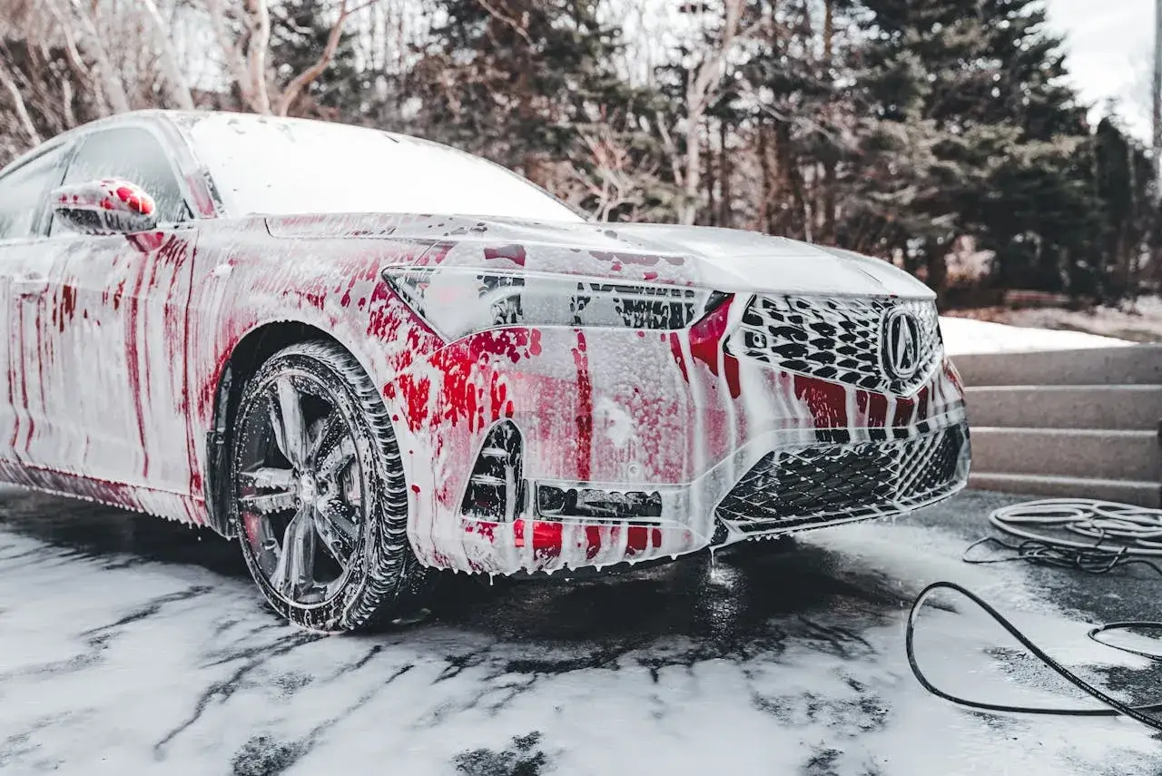 Czerwony samochód pokryty pianą, gotowy do mycia. Odpowiedź na pytanie: czy można myć auto w zimie? Tak, jeśli użyjesz odpowiednich środków.