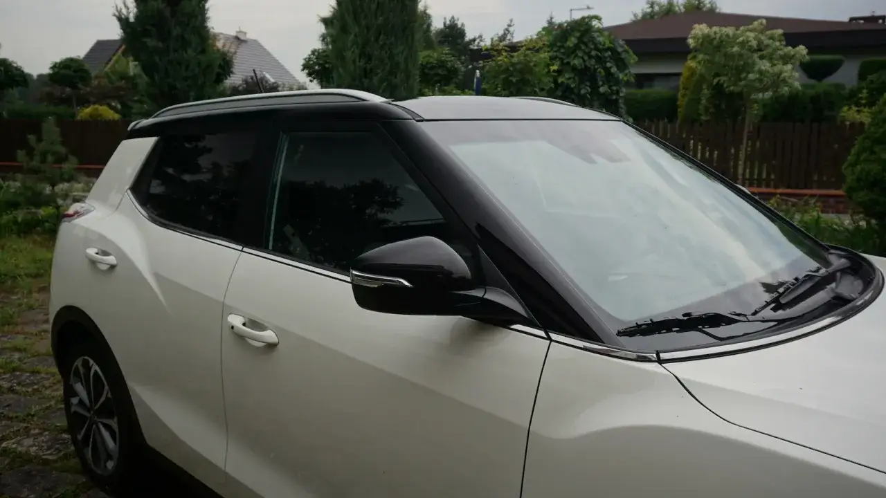 Biały SUV z czarnym oklejeniem dachu samochodu, kontrastującym z jasnym lakierem.