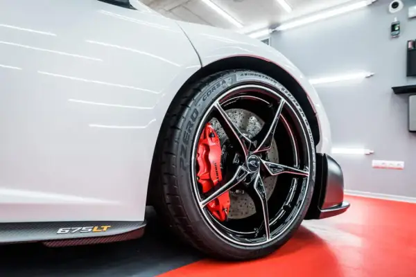 Biały McLaren 675LT z błyszczącymi felgami aluminiowymi i czerwonymi zaciskami hamulcowymi. Zabezpieczenie felg aluminiowych zapewnia im lśniący wygląd.