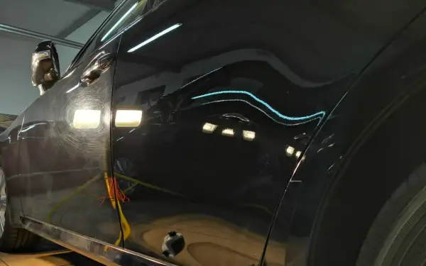 Widoczne są zarysowania i hologramy na czarnym lakierze, czekające na renowację lakieru samochodowego.