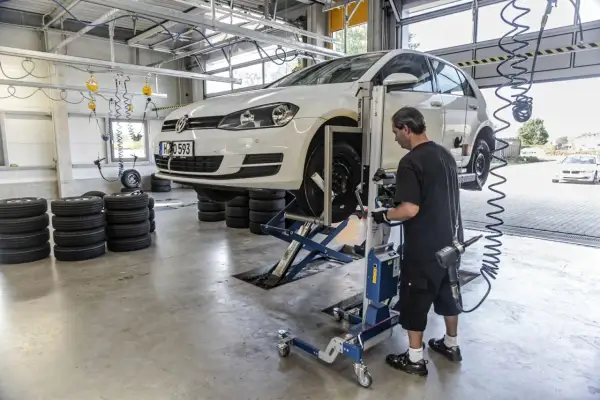 Mechanik sprawdza opony samochodu na podnośniku, przygotowując go do homologacji opon.