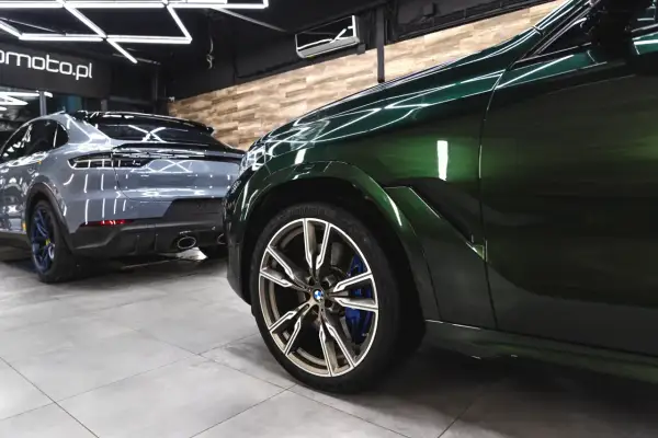 Błyszczące, zielone BMW i szary Porsche w profesjonalnym studiu auto detailing.